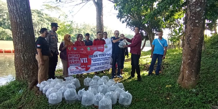 Bhabinkamtibmas Desa Timpag Ikuti Penebaran 10000 Benih Ikan Nila di Bendungan Telaga Tunjung